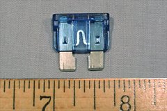 A typical automotive fuse. The short length of thin fuse wire is visible between the two spade connectors through the fuse body.